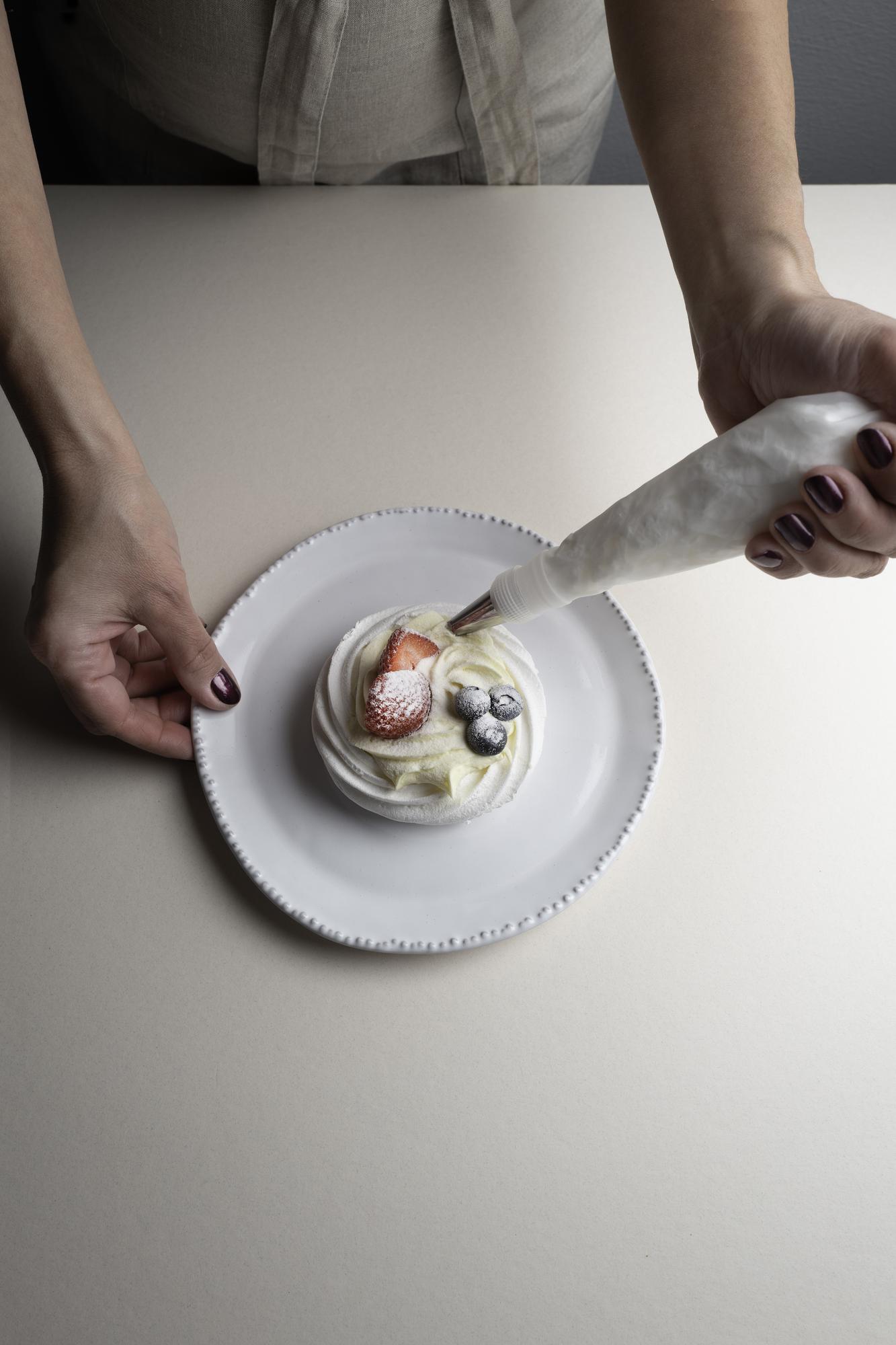 chef plating a composed dish on a neutral table